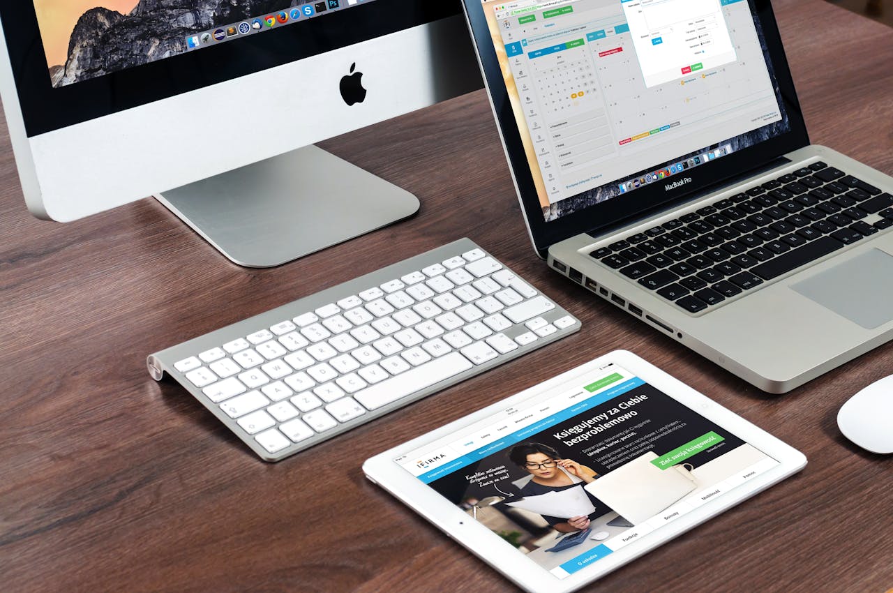 about-us A sleek office desk setup featuring Apple devices: iMac, MacBook, and iPad.